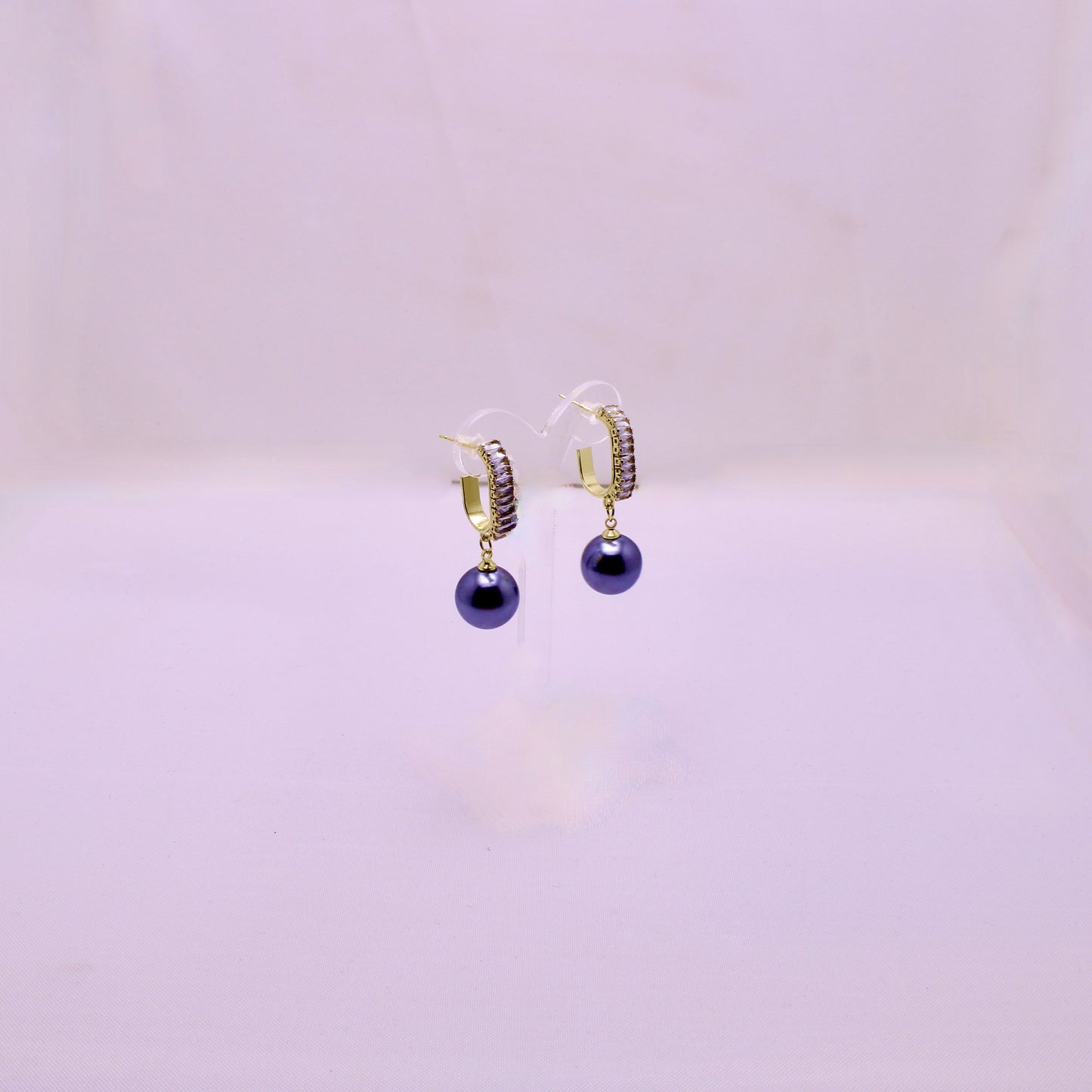 Pair of hoop earrings with purple beads on a light pink background