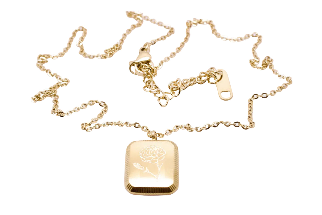 Gold necklace with a rectangular pendant on a light purple background