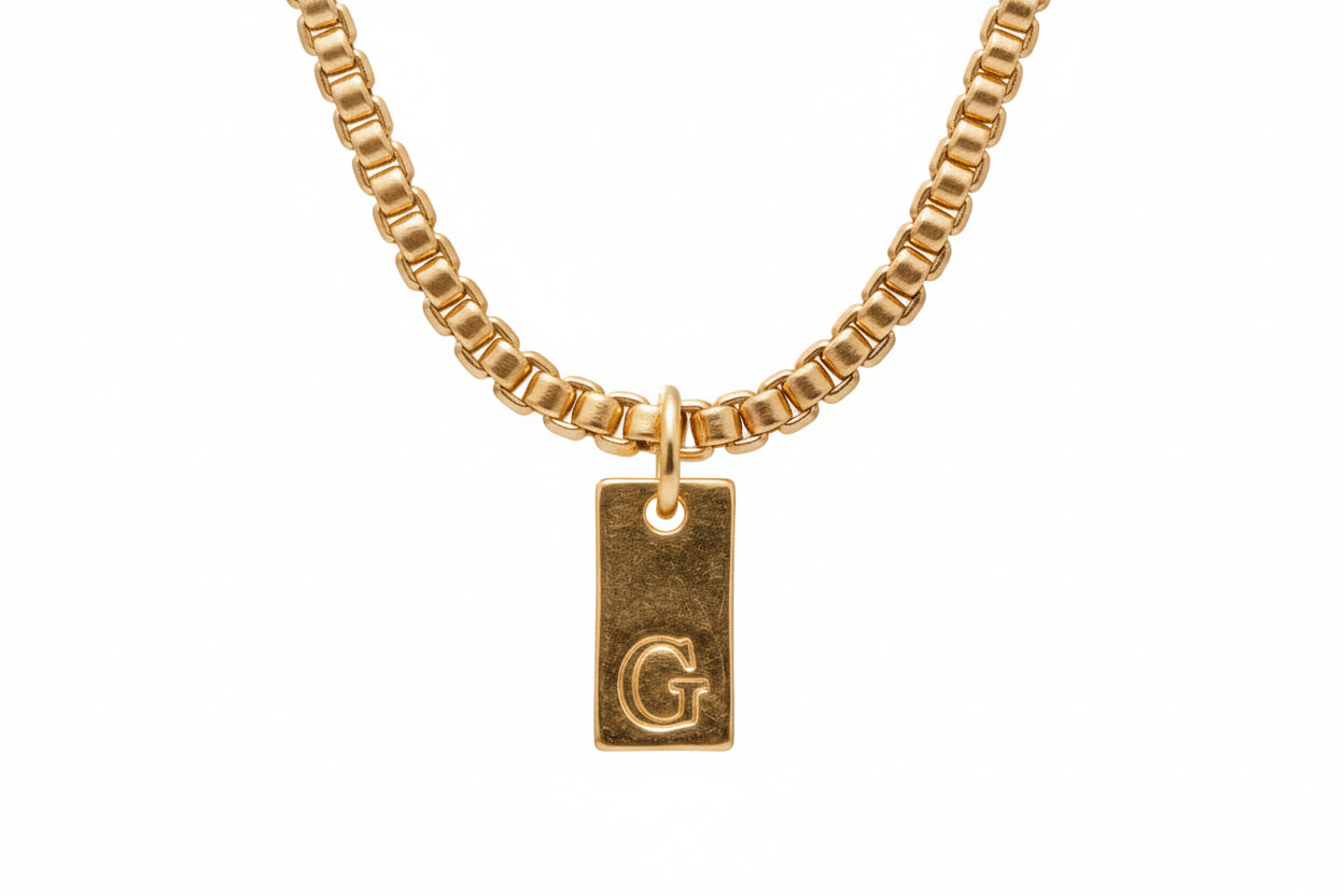 A gold-colored pendant necklace with a chain and a custom name letter pendant.