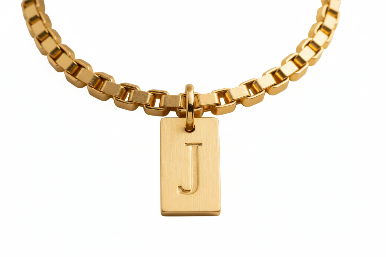 A gold-colored pendant necklace with a chain and a custom name letter pendant.