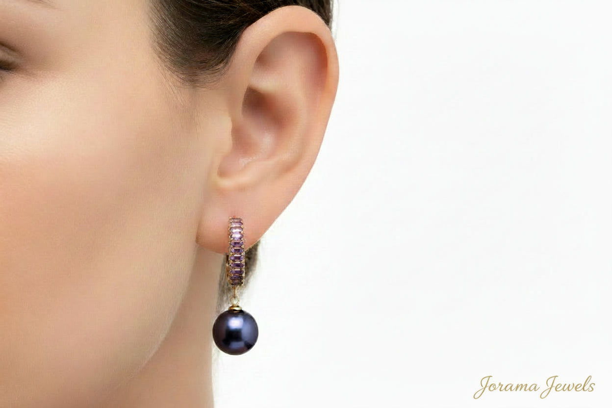 Pair of gray hoop drop earrings with purple beads on a light pink background