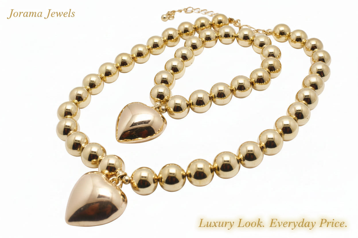 Gold beaded necklace with heart-shaped pendants on a white background