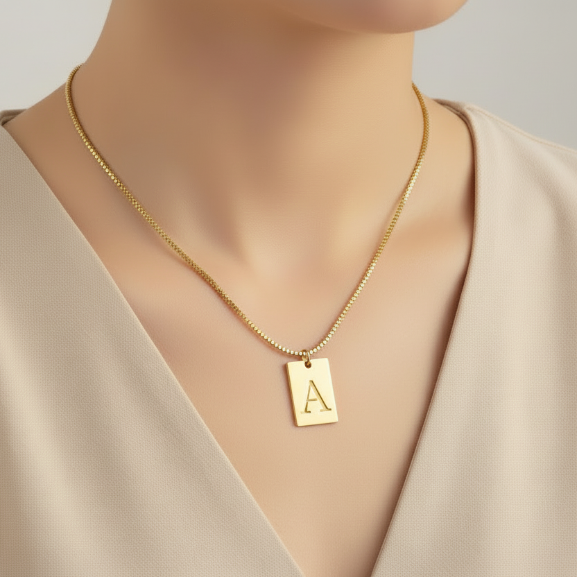 Gold necklace with a pendant on a mannequin wearing a beige top.