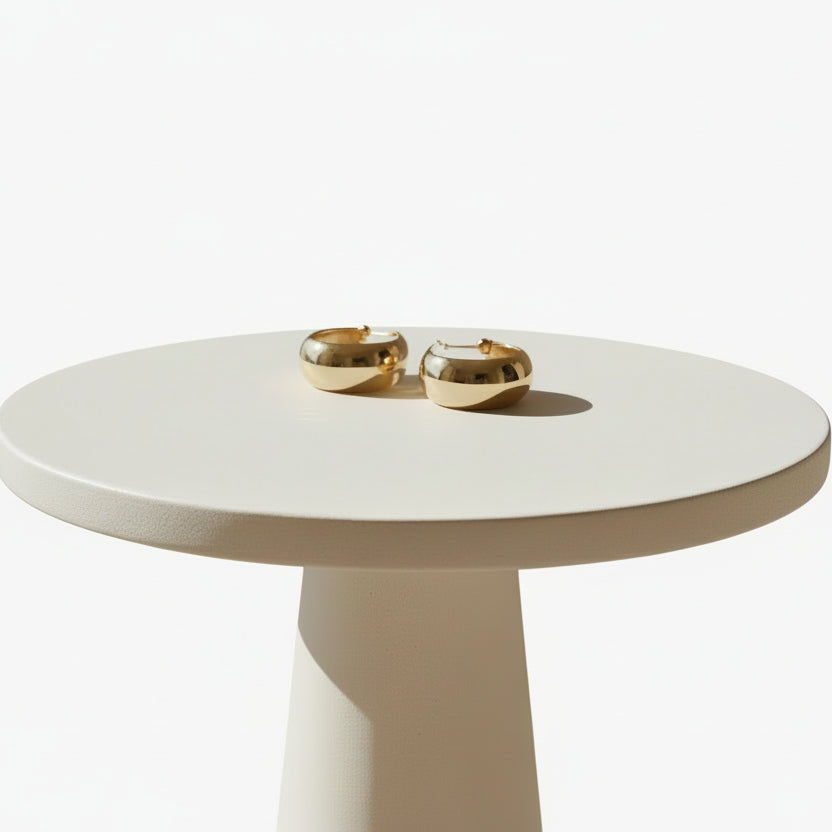Gold metal cuffs on a clear stand against a white background